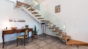 A modern interior with a glass staircase, a wooden desk, and a chair.