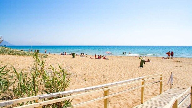 A sandy beach with a wooden boardwalk leading to the water.