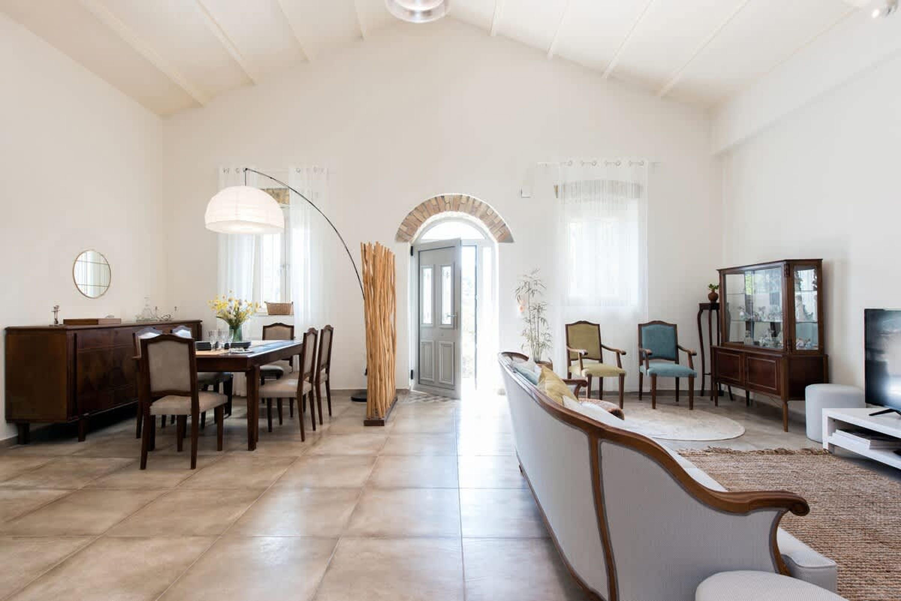 A spacious living room with a dining area, a TV, and a large window.