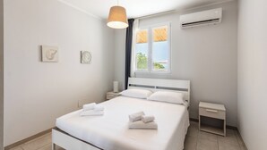 Un dormitorio moderno con una cama, mesitas de noche, una lámpara colgante y un equipo de aire acondicionado.