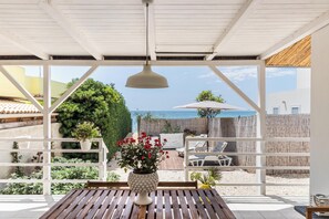 Une terrasse couverte avec une table en bois, une plante en pot et une vue sur la mer.