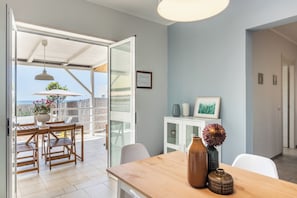 Une pièce avec une table à manger en bois, un buffet blanc et une vue sur l’extérieur.