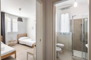 Une chambre d’hôtel moderne équipée d’un lit, d’une table de chevet et d’un espace douche.