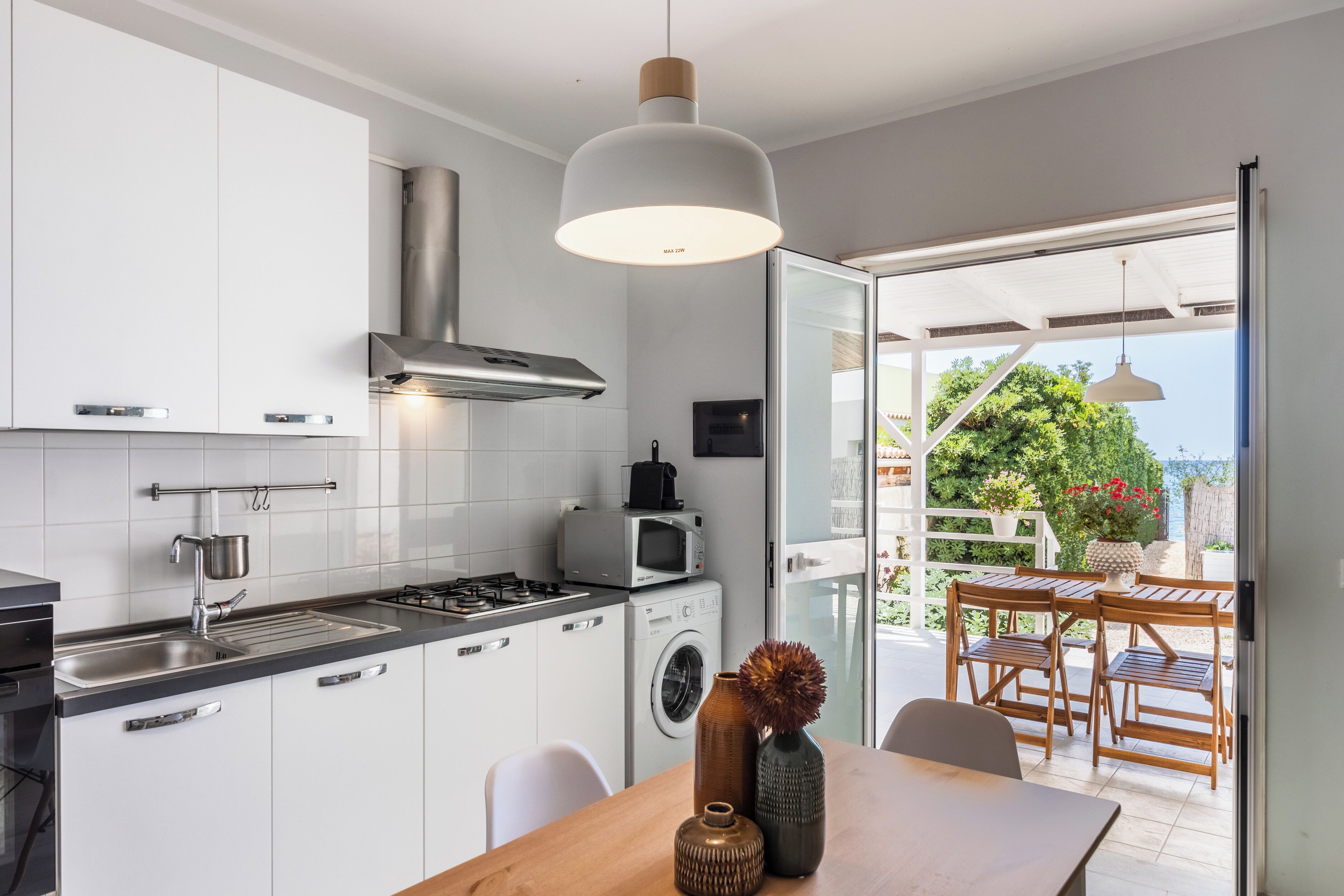 Een moderne keuken met een inbouw wasmachine, een eethoek met een tafel en stoelen, en uitzicht op de omgeving.