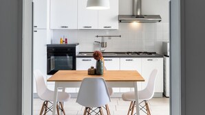 Una cocina moderna con armarios blancos, una mesa de madera y sillas blancas.