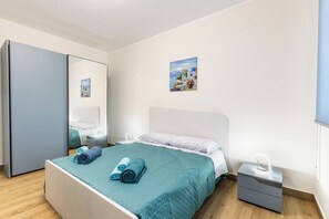 Une chambre à coucher avec un lit, une table de chevet, un miroir et un tableau accroché au mur.