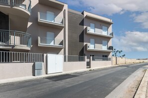 Un immeuble résidentiel à plusieurs étages, doté de balcons, d’une entrée sécurisée et surplombant un ciel dégagé.