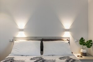 A bed with two white pillows, a wooden headboard, and two wall-mounted lights.