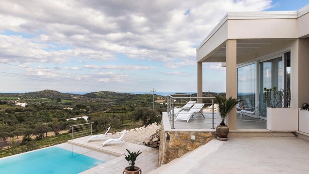 Una villa moderna con piscina, mobiliario de exterior y vistas al campo.