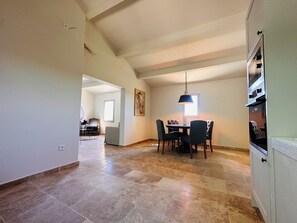 Enjoy meals in this dining area with a large table and six chairs, surrounded by a high ceiling and large window.