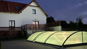 A house with a large greenhouse structure in the foreground.