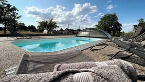 A swimming pool with lounge chairs and a covered area.