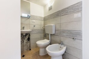 Une salle de bain équipée de toilettes, d’un bidet et d’un lavabo.