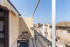 A balcony with a table and chairs, a railing, and a view of historic buildings.