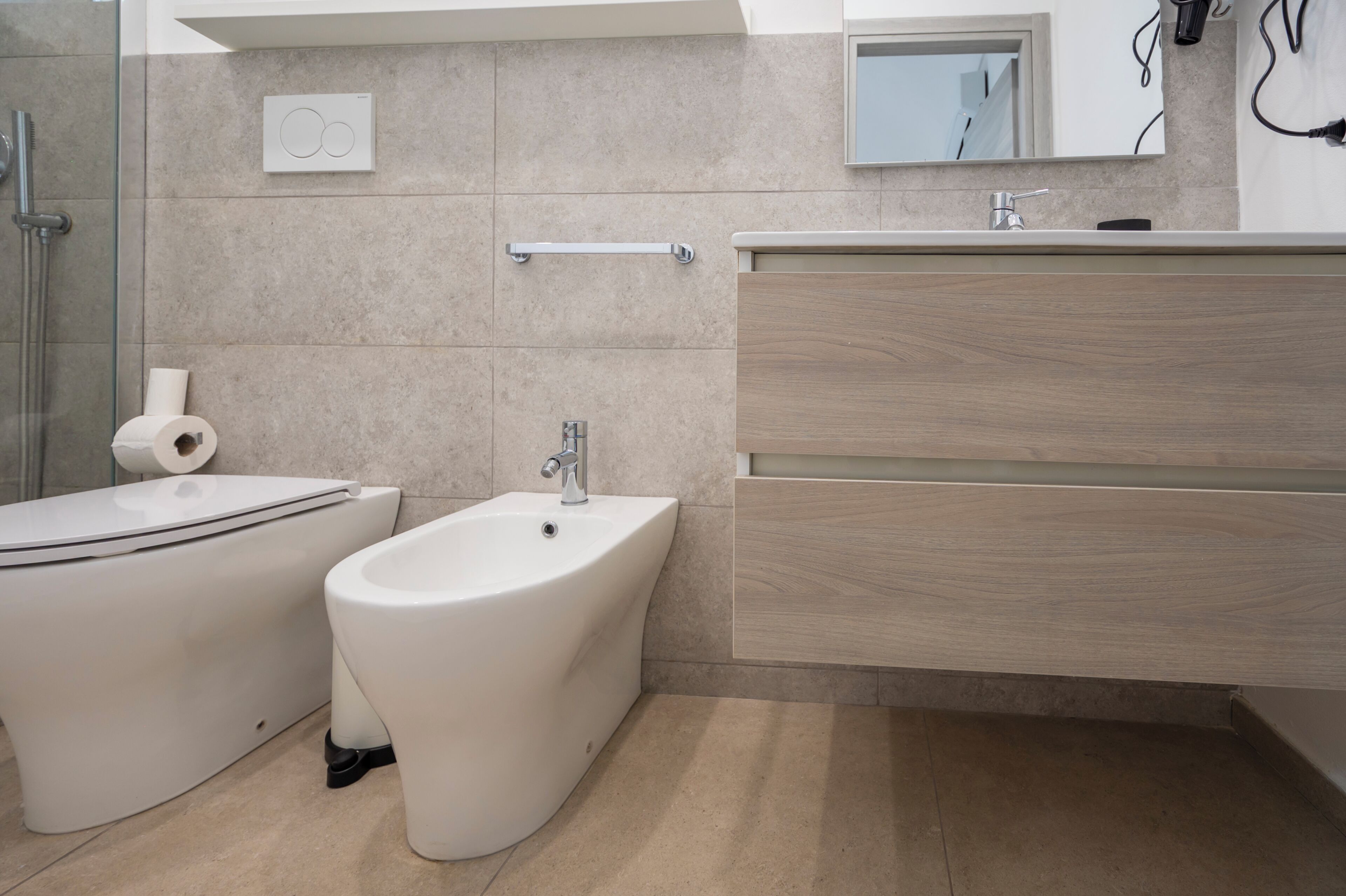 Ein modernes Badezimmer mit Toilette, Bidet und einem Waschtisch mit Spiegel.