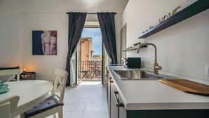 A modern kitchen with a dining area, a view to the outside, and a small balcony. - Demetra - One Bedroom Apartment, Sleeps 4 (Noto)