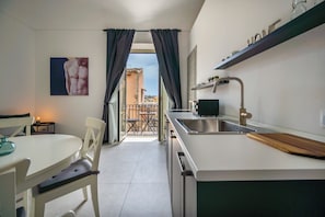A modern kitchen with a dining area, a view to the outside, and a small balcony.