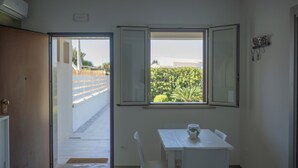 Ein Zimmer mit Esstisch, Fenster mit freiem Blick und einer Tür, die nach draußen führt.