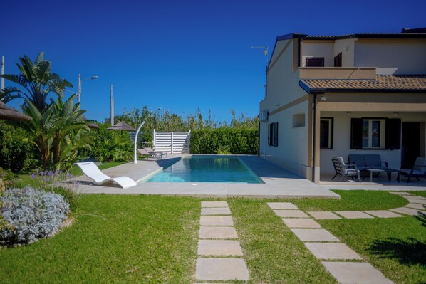 A modern house with a swimming pool, a patio with lounge chairs, and a well-maintained garden. - Villa Zuzana - Two Bedroom Apartment, Sleeps 4 (Calabernardo)