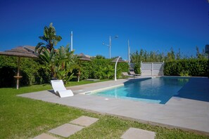 A swimming pool with lounge chairs, a thatched-roof structure, and lush greenery. - Villa Zuzana - Two Bedroom Apartment, Sleeps 4 (Calabernardo)