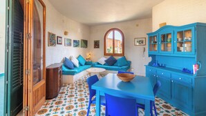 A room with a blue table, chairs, a sofa, a cabinet, and a patterned floor.