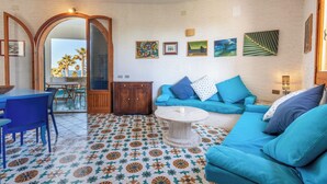 A living room with a blue sofa, a round coffee table, and a tiled floor with a floral pattern.