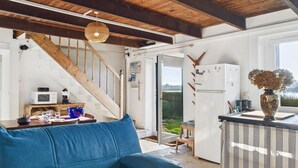 Ein gemütliches Wohnzimmer mit einem blauen Sofa, einer Holztreppe und Blick ins Freie.