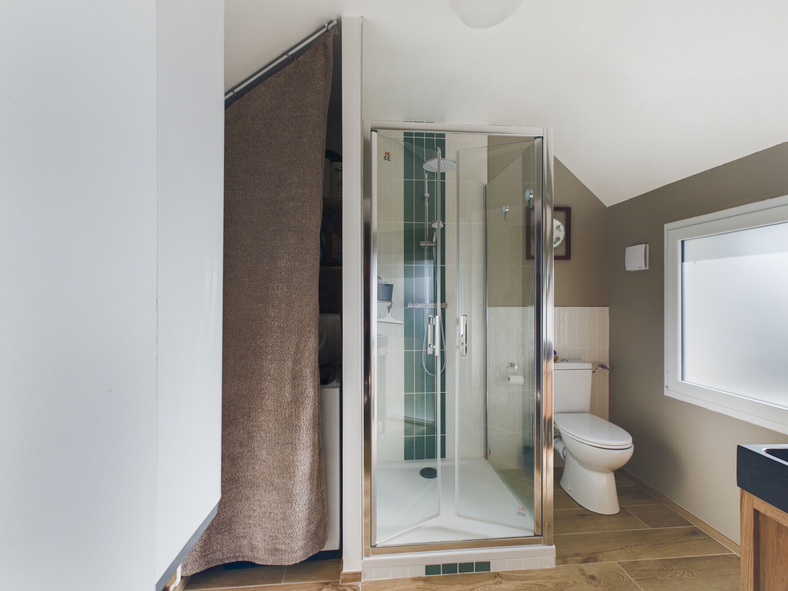 A modern bathroom with a glass-enclosed shower, a toilet, and a sink.