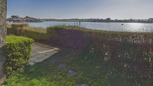 Blick auf einen See mit Booten, einer Steinmauer und viel Grün.
