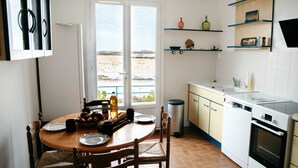 Una cocina con una mesa de comedor, sillas y vista al mar por la ventana.