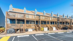 A row of wooden cabins with balconies, a covered outdoor seating area, and a parking lot.