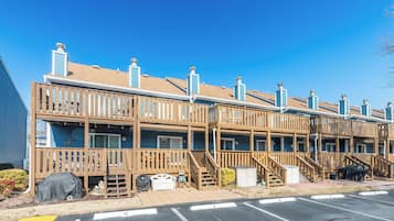 A row of wooden cabins with balconies, a covered outdoor seating area, and a parking lot.