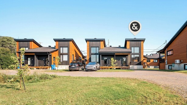 A modern residential complex with multiple two-story houses featuring large windows and a mix of wood and metal exteriors.