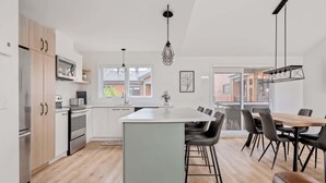 A modern kitchen with a central island, white cabinets, and a dining area with a wooden table and black chairs.