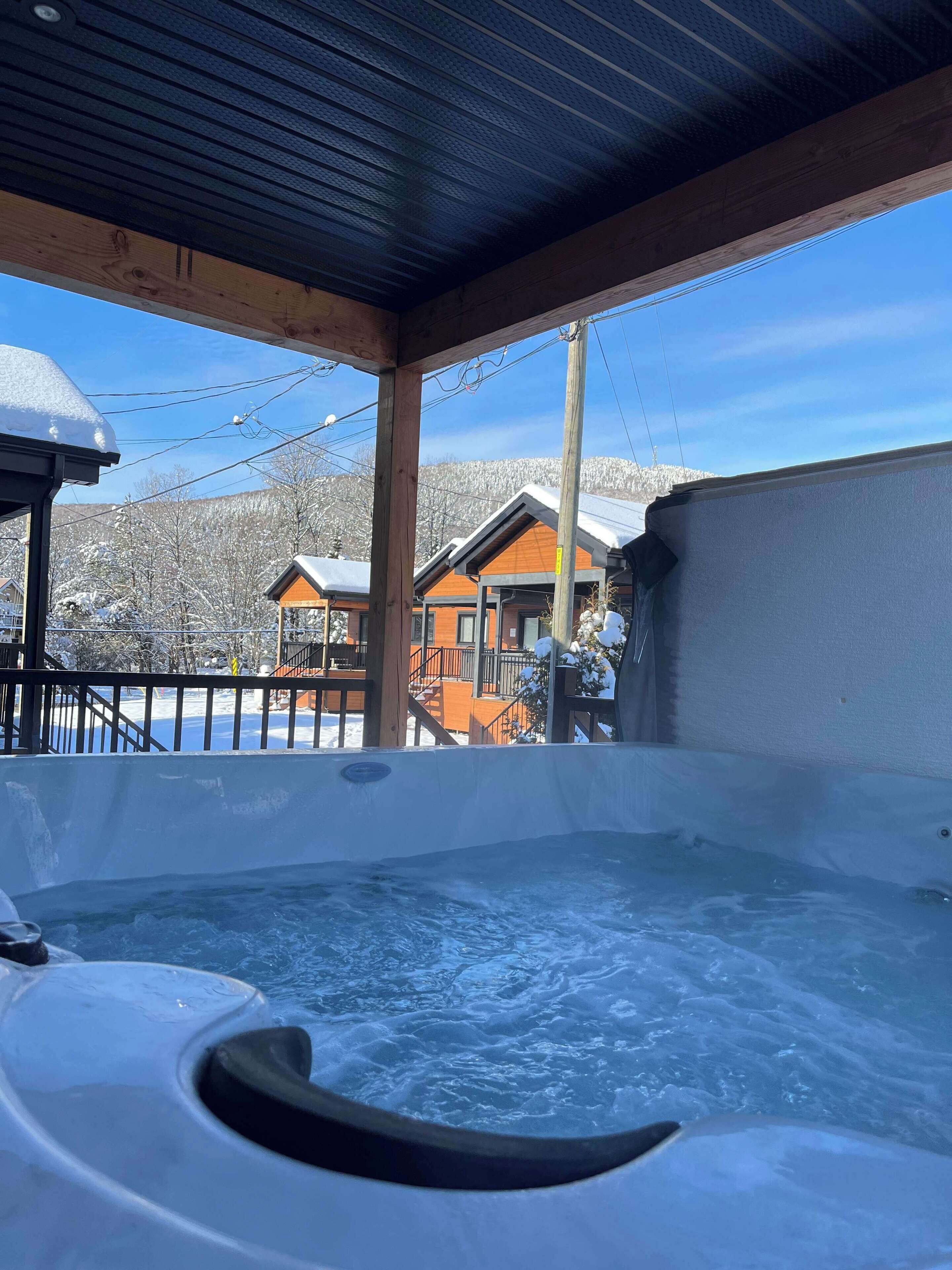 A hot tub with a view of snow-covered houses and mountains in the background.