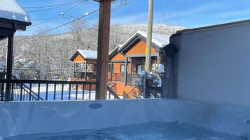 A hot tub with a view of snow-covered houses and mountains in the background.