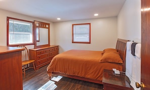 Un dormitorio con cama, cómoda, silla y ventana con persianas.