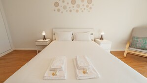A neatly made bed with white linens, two bedside tables with lamps, and a wall decor of circular patterns.