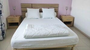 A neatly made bed with a quilted blanket, two pillows, and two bedside tables with lamps. - Cosy house near the sea (Hermanville-sur-Mer)
