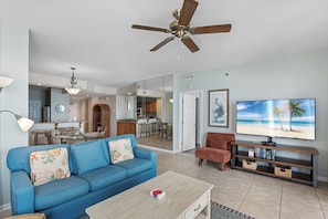 A living room with a blue sofa, a coffee table, a TV, and a ceiling fan.