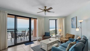 Ein geräumiges Wohnzimmer mit Balkon, Deckenventilator, Couchtisch, Sofa und Lampe.