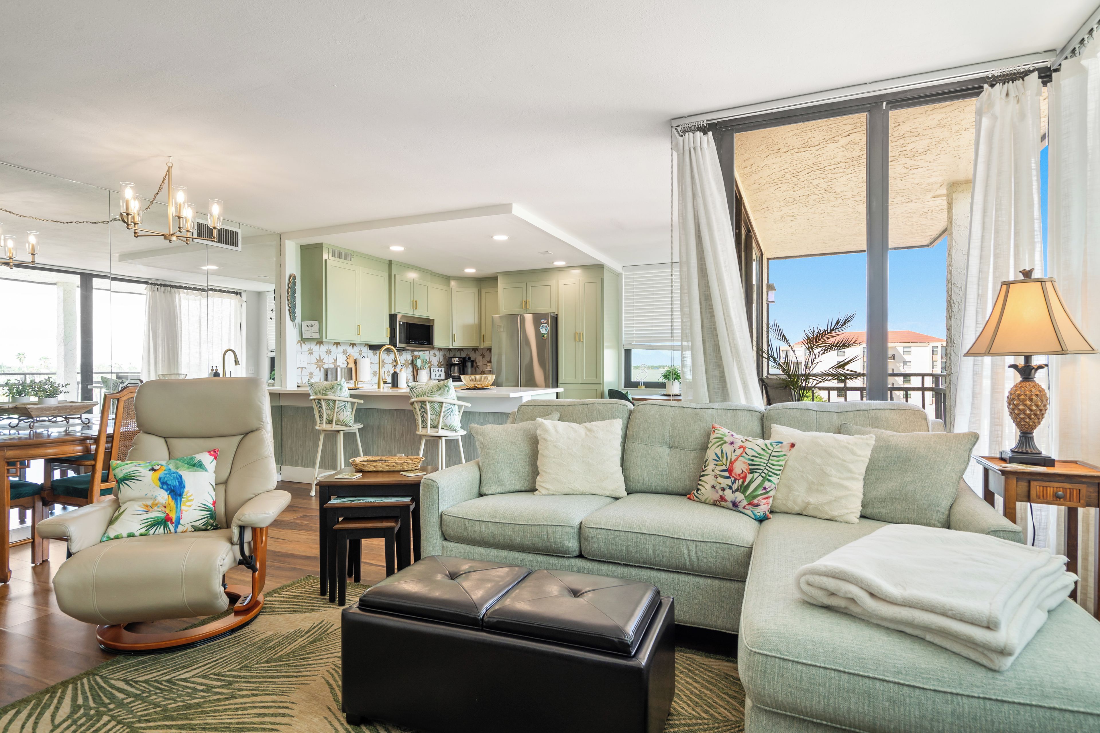A modern living room with a sofa, ottoman, and a dining area with chairs and a table.
