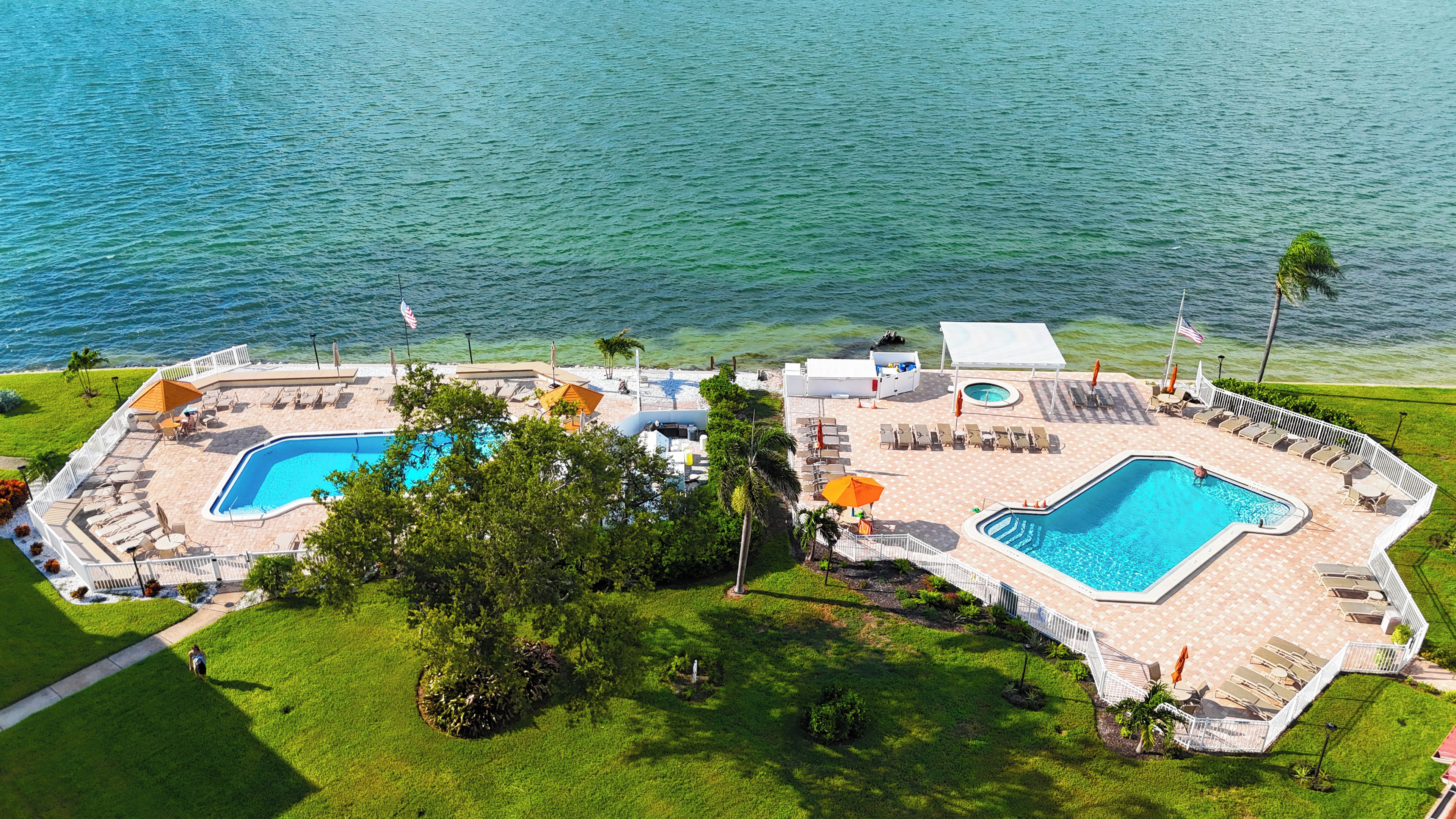 A resort with two swimming pools, sun loungers, umbrellas, and a view of the sea.
