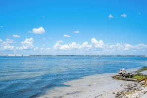 Eine Küstenlandschaft mit klarem Himmel, ruhigem Wasser und einem Sandstrand mit Felsen.