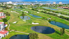 Ein Golfplatz mit mehreren Teichen, Wegen und umgebenden Gebäuden.