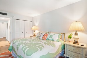 Ein Schlafzimmer mit einem Bett, Nachttischen, einer Lampe und einem Kleiderschrank.