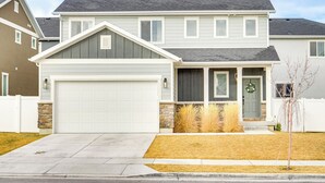 A two-story house with a garage, a front porch, and a stone foundation. - 4 Mi to Zions Bank Stadium: Sleek Herriman Retreat (Herriman)