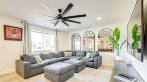 A modern living room with a sectional sofa, ottomans, a ceiling fan, large windows, and a potted plant. - Families w/ Pets Welcome! Home 4 Mi to Dtwn Tempe (Tempe)