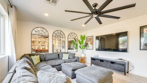 A modern living room with a sectional sofa, ottomans, a ceiling fan, a large flat-screen TV, and a decorative plant. - Families w/ Pets Welcome! Home 4 Mi to Dtwn Tempe (Tempe)