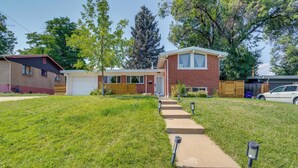 A two-story brick house with a front yard, a garage, and a driveway leading to the house. - 10 Mi to Red Rocks: Denver Home w/ Fire Pit! (Denver)